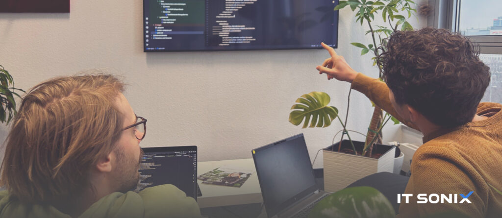Zwei Mitarbeitende der IT Sonix GmbH besprechen Quellcode während der Softwareentwicklung.