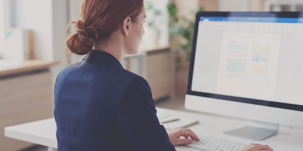 Woman in a blue blazer in front of a desktop computer