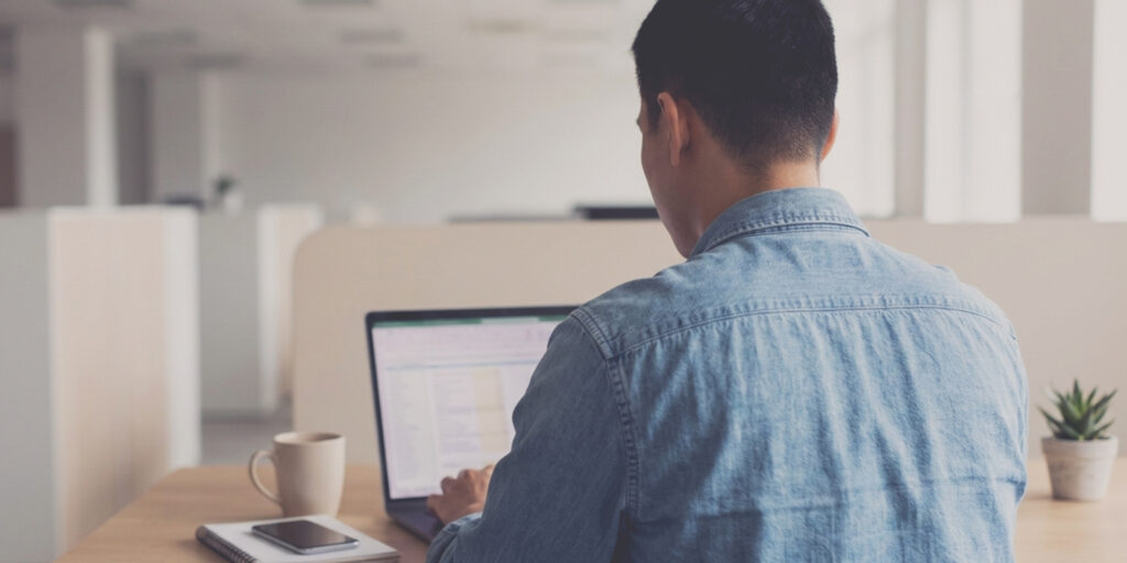 Man in a blue shirt sitting in front of a laptop